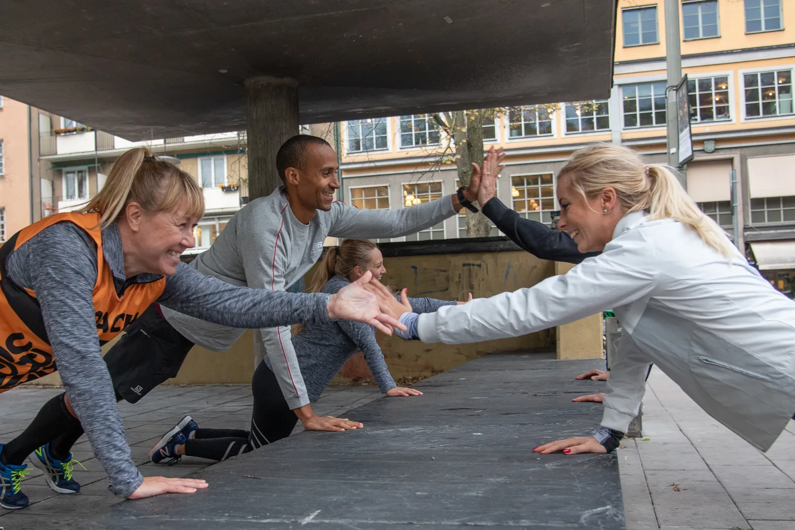 En coach i orange Urban Tribes-tröja ger en deltagare en high five under ett pass
