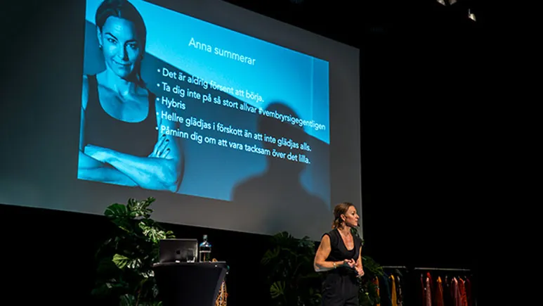En föreläsare på scen framför en storbild med sina tips, ur Urban Tribes presentation