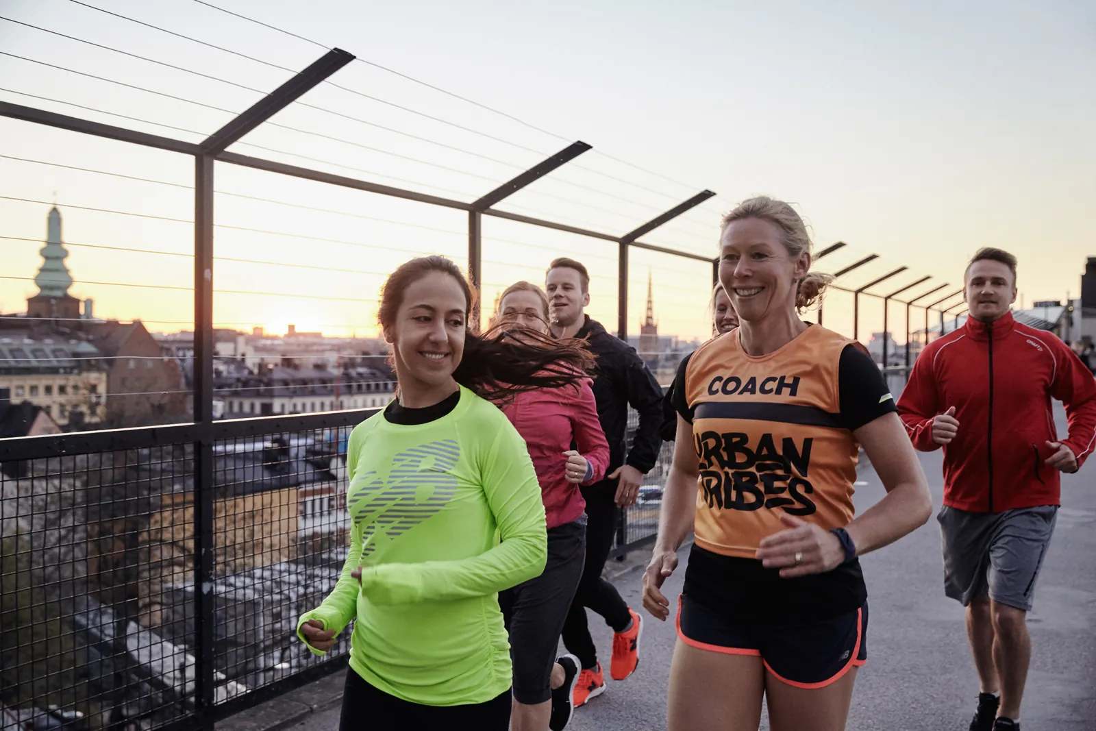 En löpgrupp från Urban Tribes springer genom Stockholm, coachen i orange tröja främst