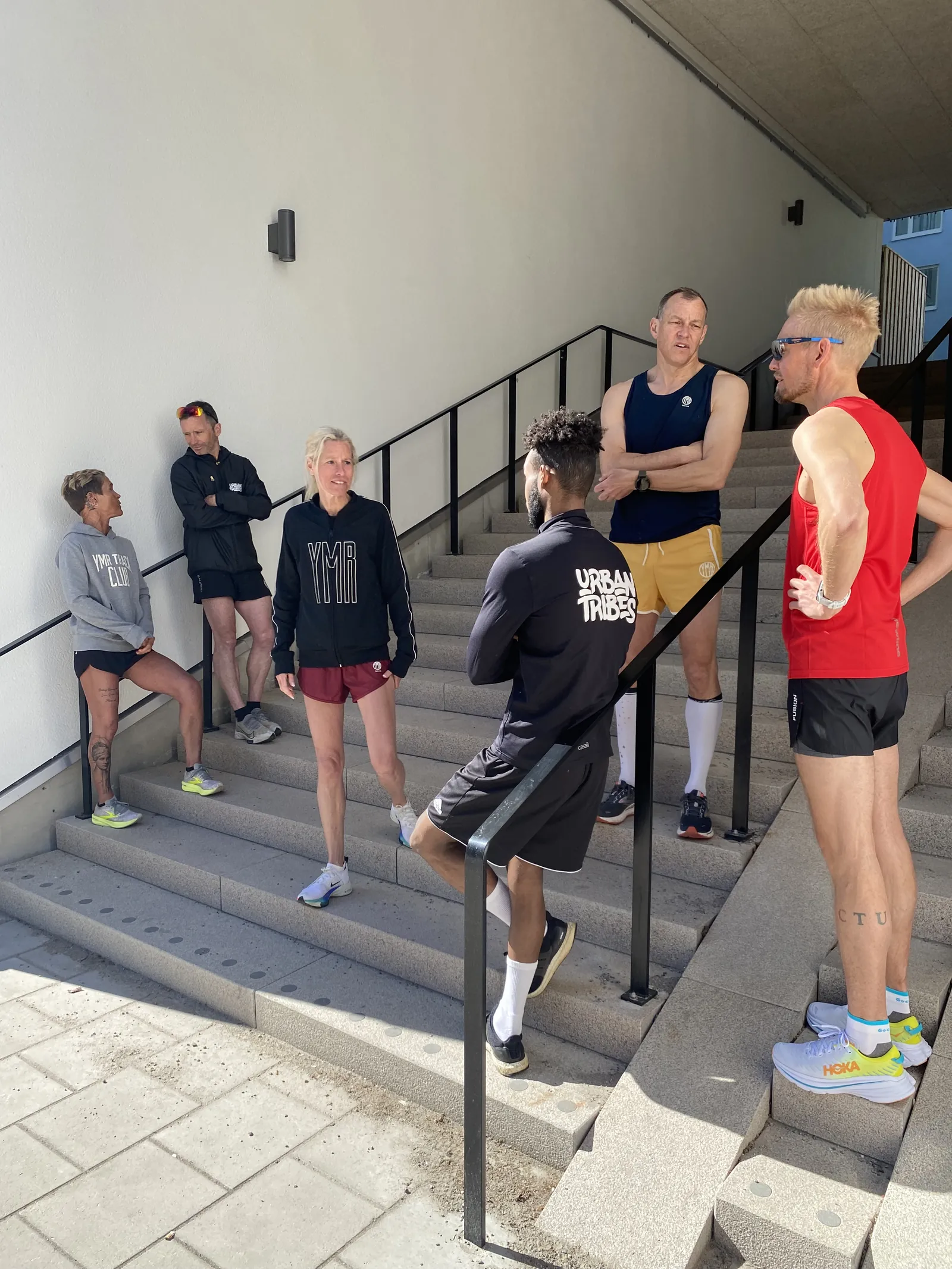En hel löpgrupp hänger i en trappa efter passet, i orange och gröna Urban Tribes-tröjor