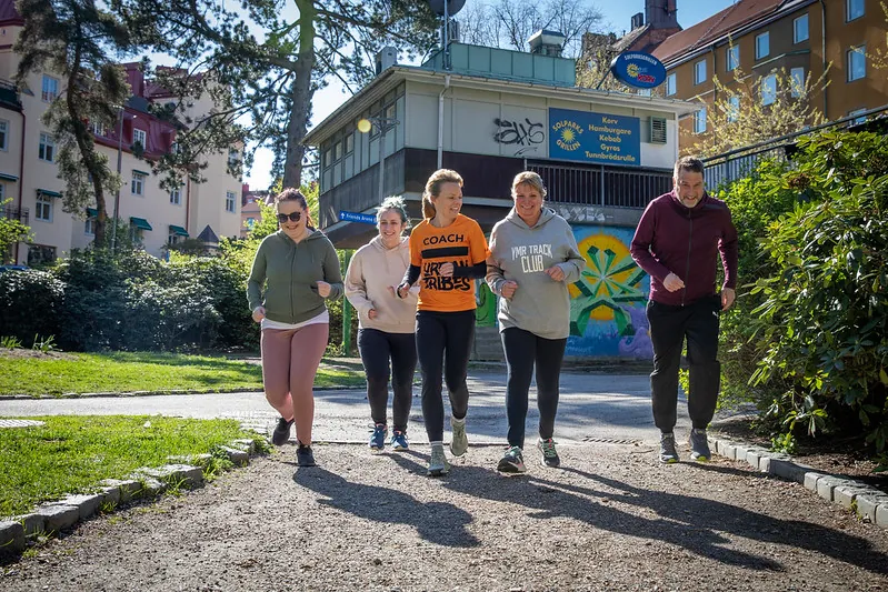En grupp nybörjare joggar i lugnt tempo genom en park
