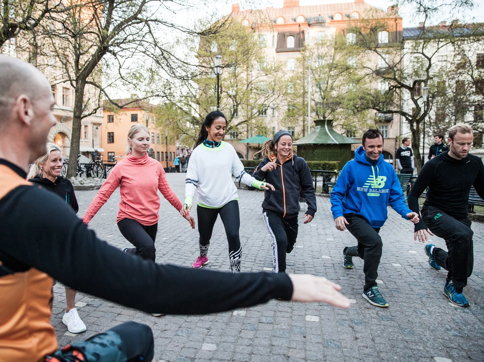 En hel grupp kollegor kör Total Body Workout på ett torg i Stockholm, coachen längst fram