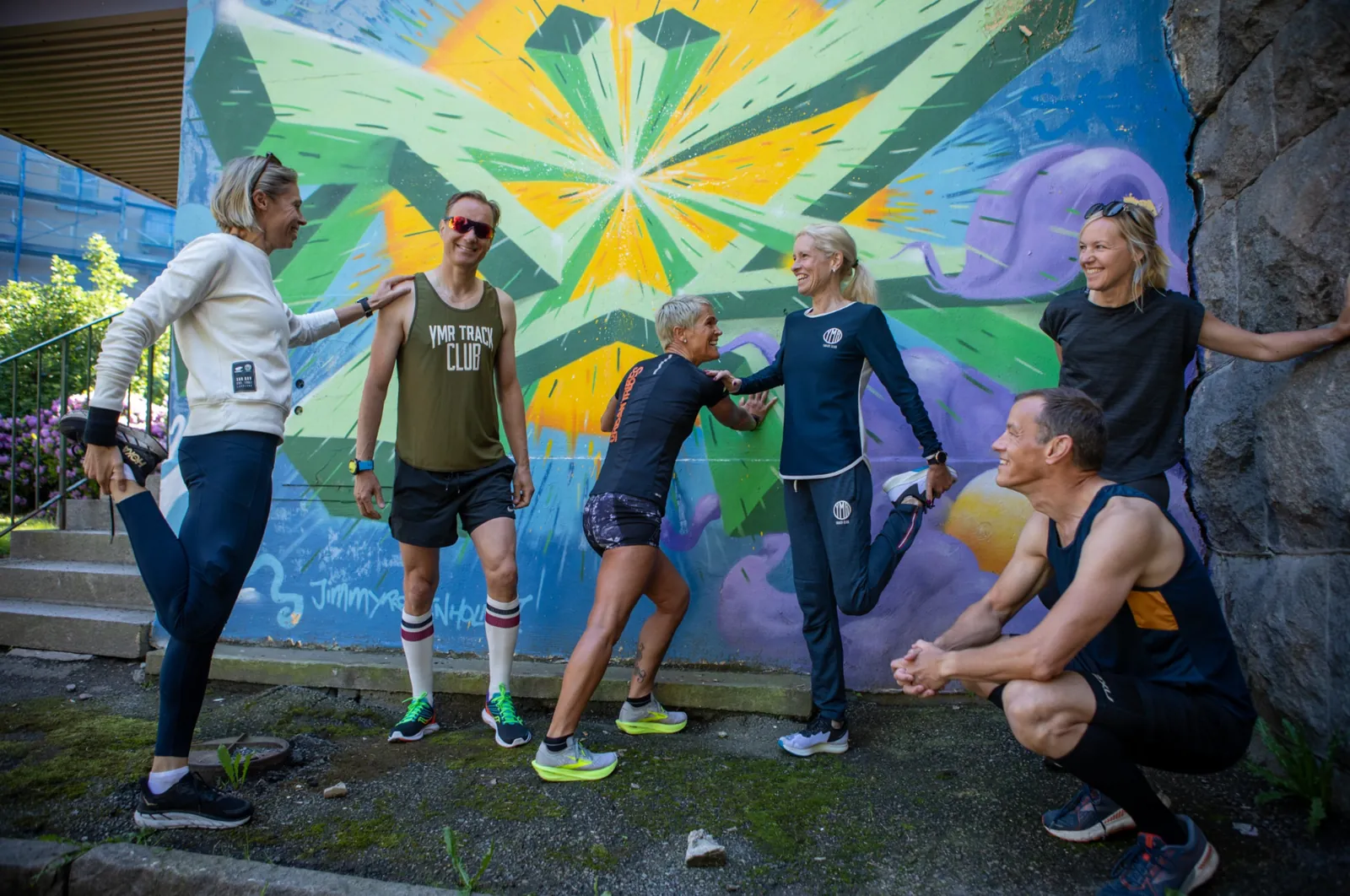 En hel arbetsplats tränar tillsammans framför en färgglad muralmålning